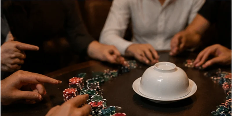 A group watches the bowl being prepared, illustrating the sequence of a traditional xoc dia round.